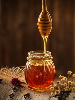 Honey drips from wooden spoon Original